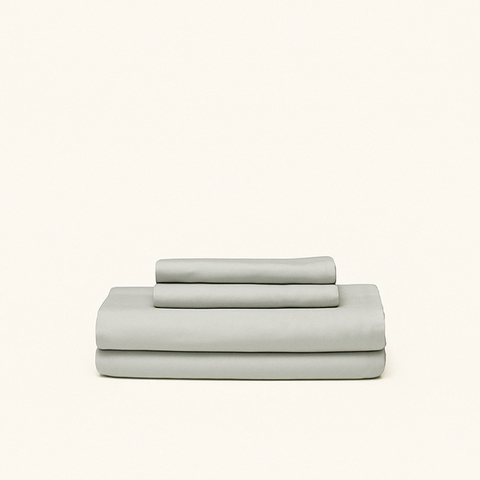 Mid-tone gray cooling sheets designed with cooling technology and moisture-wicking fabrics folded on a cream background.
