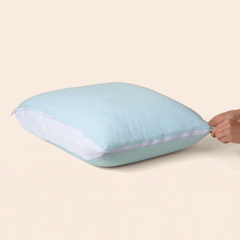 A gif of the Adjustable UltraCool Pillow being unzipped on a cream background