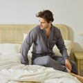 A young man sitting on the edge of his bed made with Avec linen-blend sheets