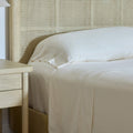 The sun shining on a neatly made bed with Avec bedding linen-blend sheets