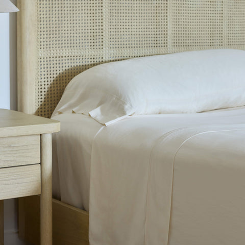 The sun shining on a neatly made bed with Avec bedding linen-blend sheets