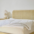 An Avec Goods Down Alternative Duvet Insert lying on the corner of a bed