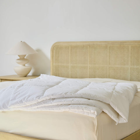 An Avec Goods Down Alternative Duvet Insert lying on the corner of a bed