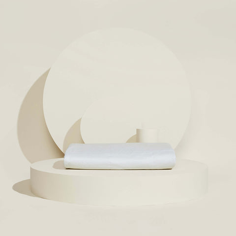 A folded Slumber Cloud Core Mattress Protector on a cream background