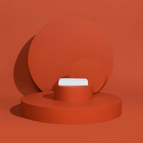 A folded Slumber Cloud Essential Fitted Sheet - Crib on a red background