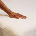 A man touching the outer fabric of the Slumber Cloud Performance Mattress Pad
