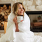 Woman holding her coffee while wrapped in the Slumber Cloud UltraCool Comforter takes the ClimaDry™ by Outlast and pairs it with an 89% cooling nylon and 11% spandex outer cover that mimics silk creating the silky smooth and soft to the touch hand feel.  |  rollover