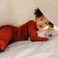 A child holding a teddy bear lying under the Slumber Cloud Comforter made with temperature regulation technology