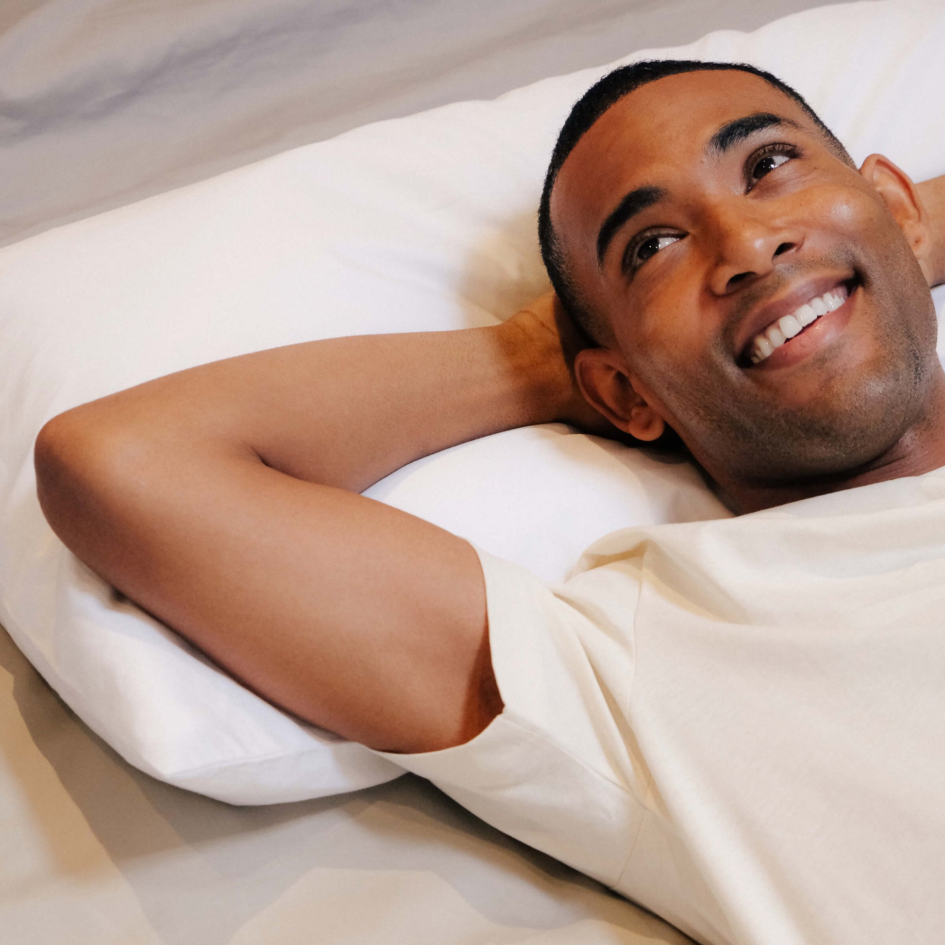 A man smiling and laying on a Slumber Cloud Core Down Alternative Pillow