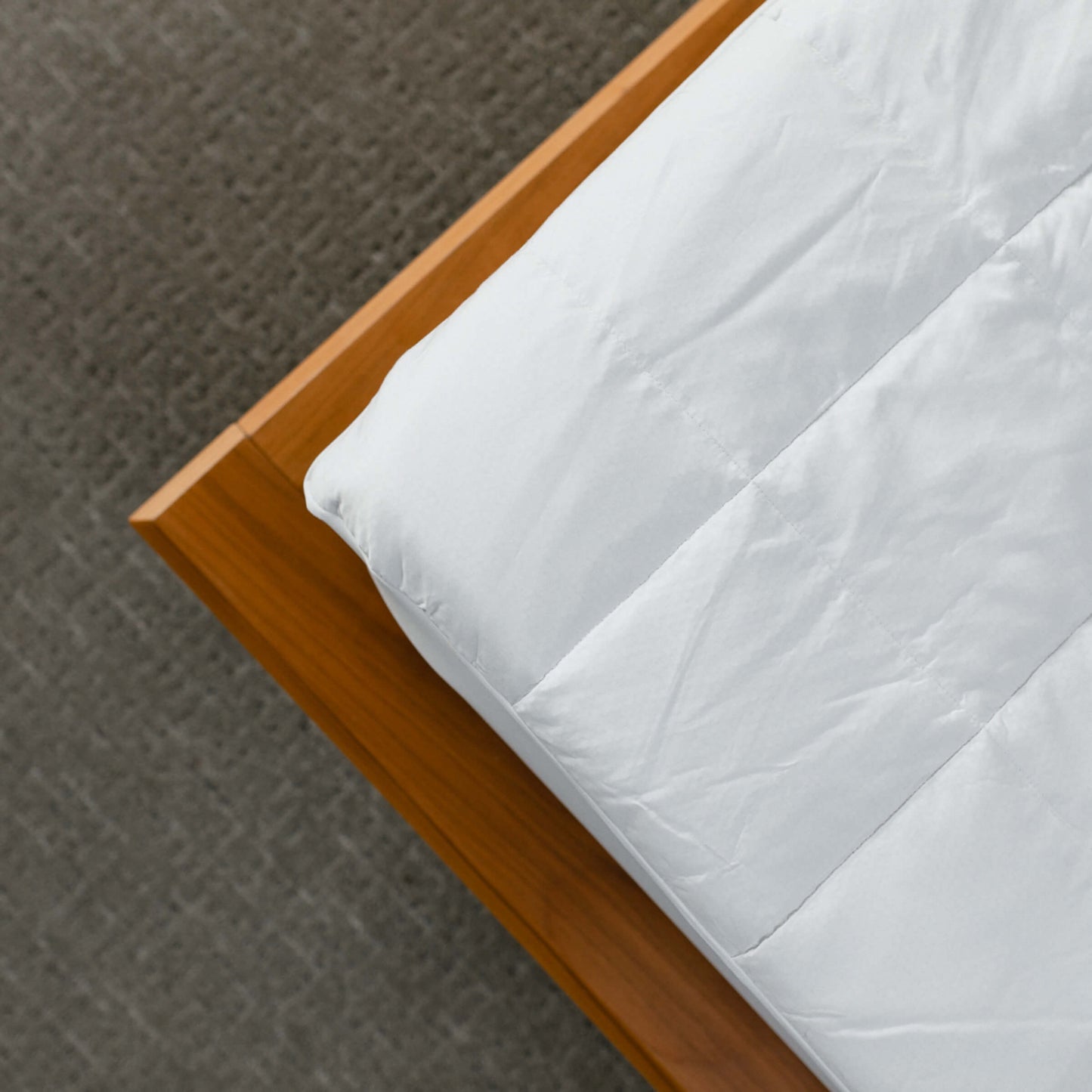 Detailed view of the Slumber Cloud Core Mattress Pad on a wood framed bed