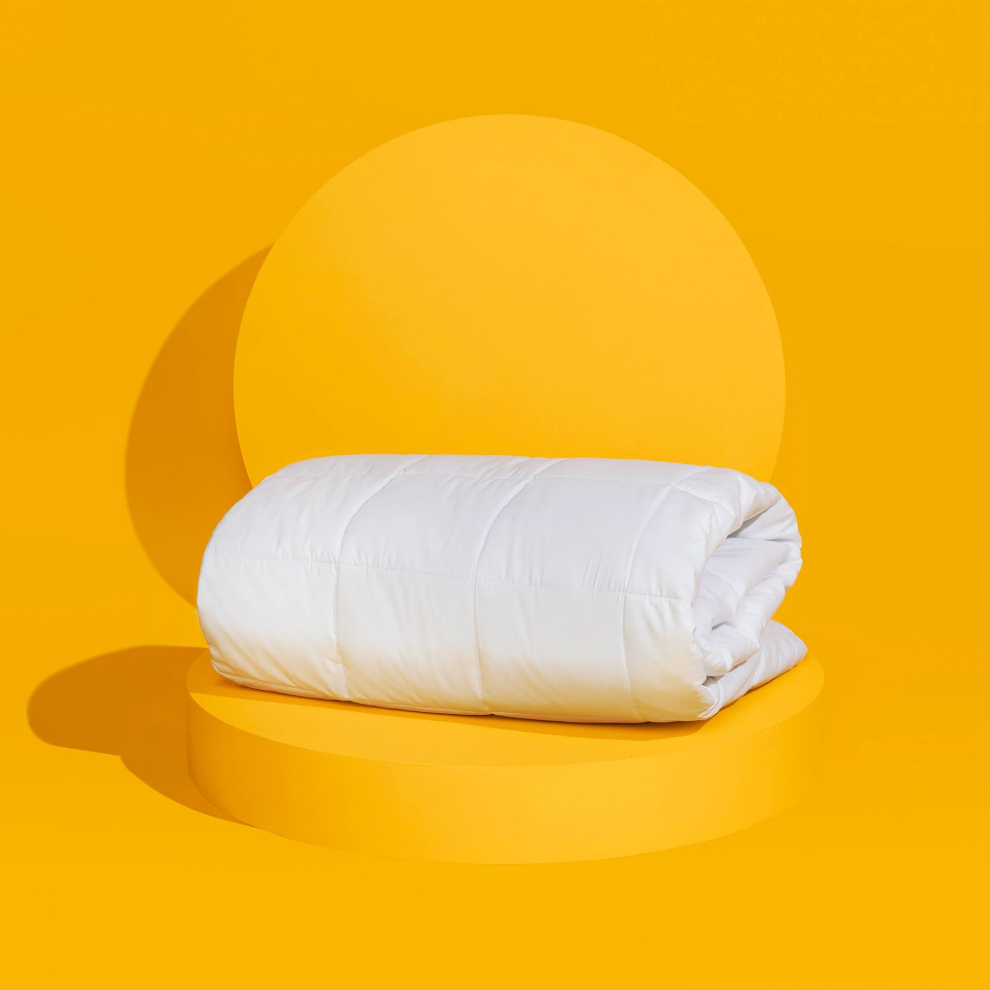 The temperature regulating Core Mattress Pad from Slumber Cloud propped on a yellow background
