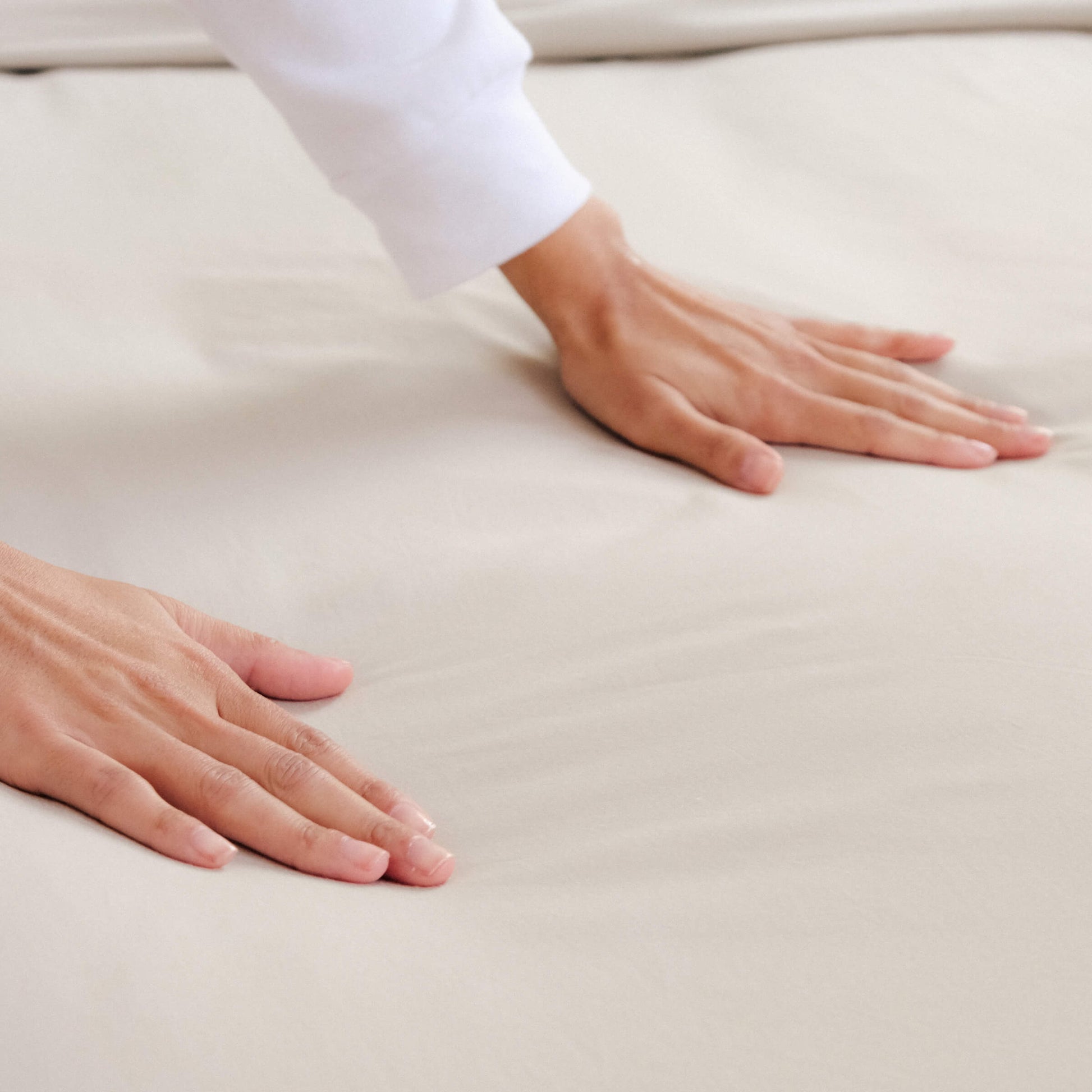 Woman touching the Slumber Cloud Essential Sheet Set made with temperature regulation technology