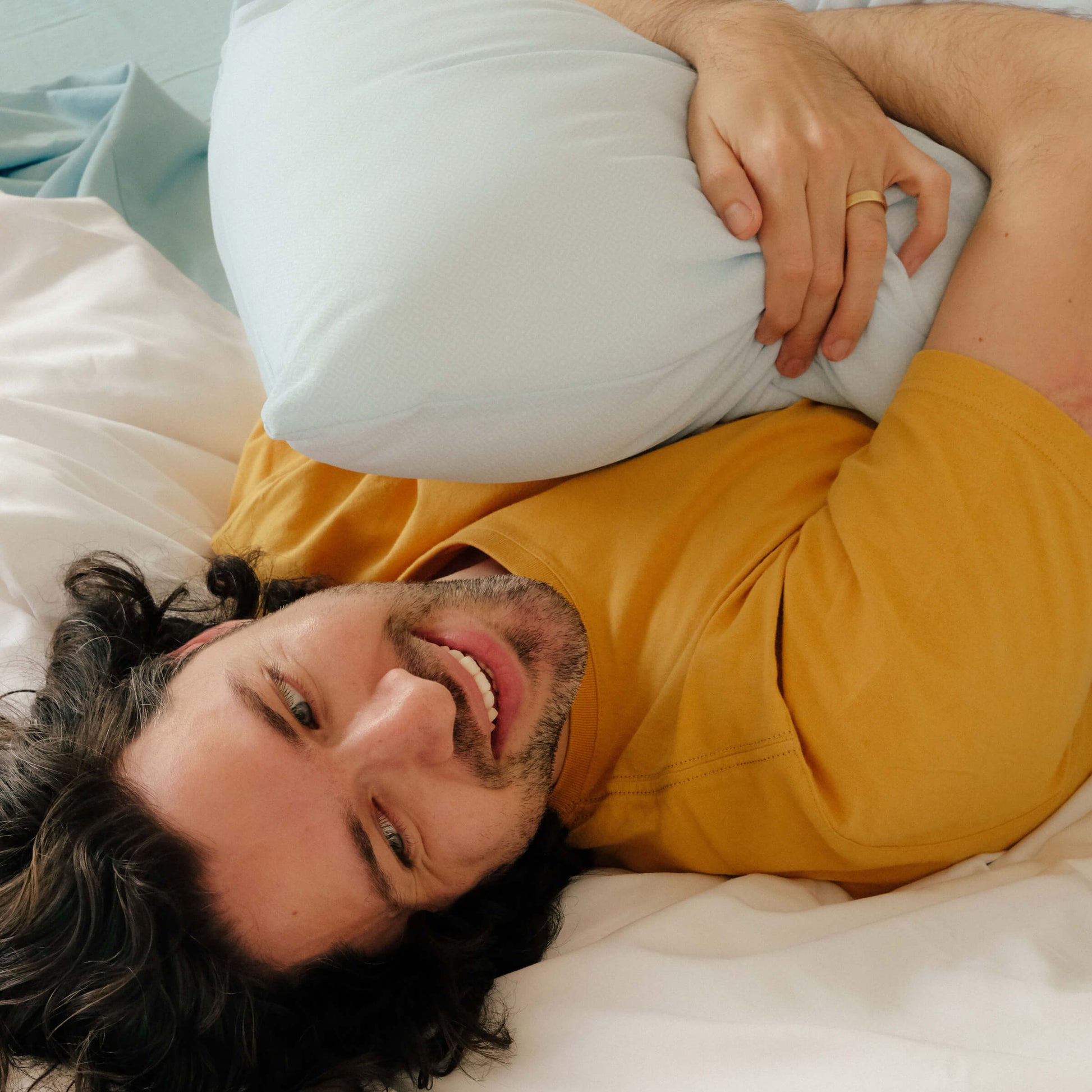 Man lying on his bed while hugging the Slumber Cloud UltraCool Pillow made with Outlast Temperature Regulation Technology
