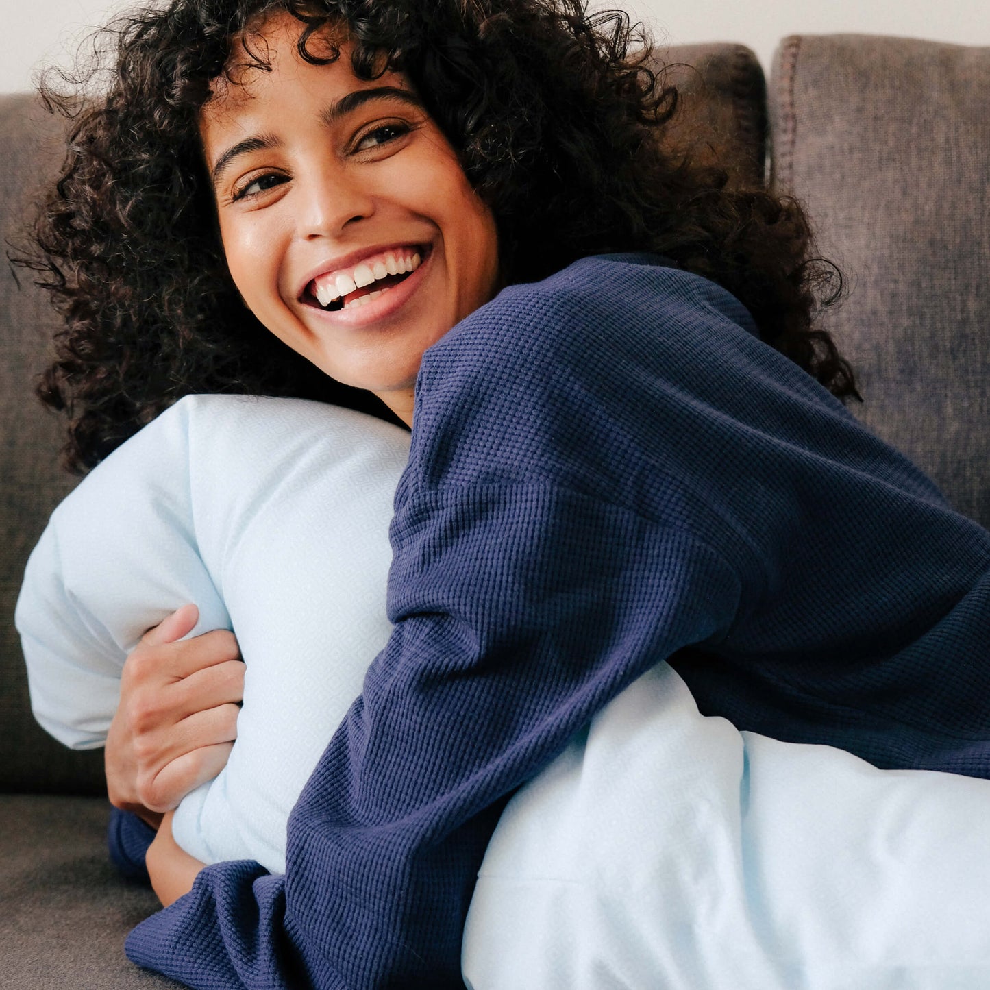Woman lying on the couch while hugging the Slumber Cloud UltraCool Pillow made with Outlast Temperature Regulation Technology