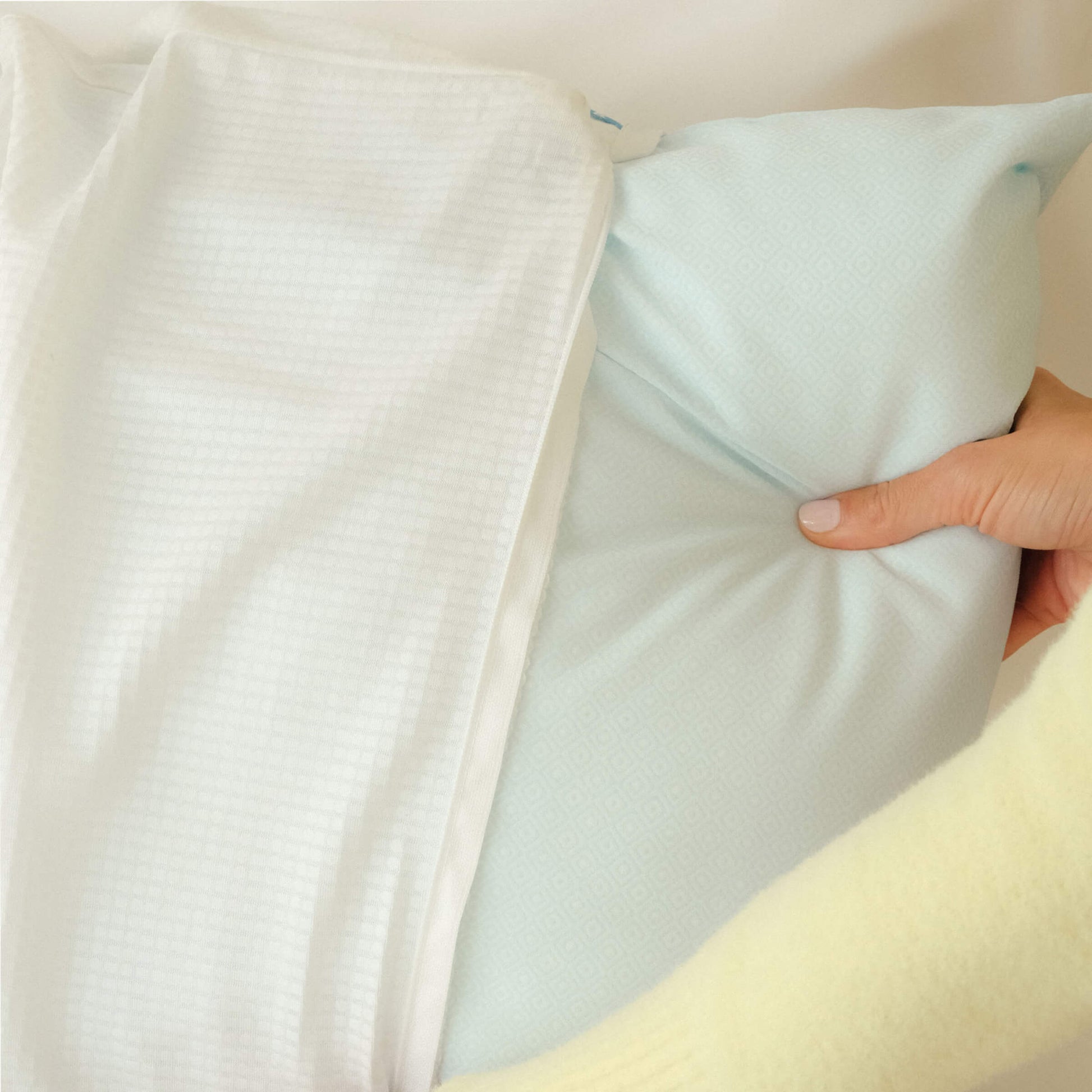 A woman inserting the UltraCool Pillow into the Slumber Cloud Performance Pillow Cover with Outlast temperature regulation technology