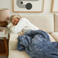 A woman lying on the couch with the Slumber Cloud Plush Throw Blanket made with Outlast Temperature regulation technology