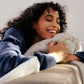A woman lying on the couch with the Slumber Cloud Plush Throw Blanket made with Outlast Temperature regulation technology